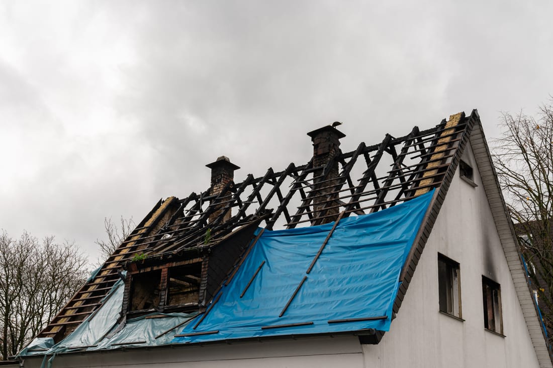 Storm-damaged roof under emergency tarp following Hurricane Helene